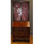 A late George III walnut small bureau having four long drawers with brass handles raised on