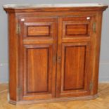 A 19th century oak wall cupboard, the moulded cornice over a pair of mahogany banded fielded panel