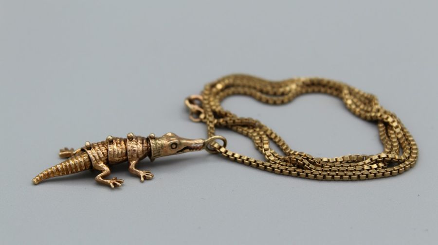 An articulated alligator/crocodile pendant in 9ct gold on a 24 inch box link necklace in yellow