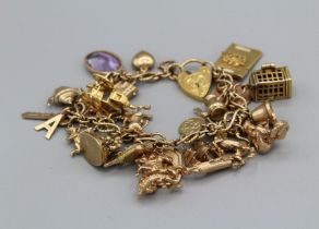 A 9ct gold charm bracelet containing twenty four charms to include an articulated carriage, a