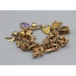 A 9ct gold charm bracelet containing twenty four charms to include an articulated carriage, a