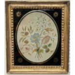 An early 19th century floral silkwork, the oval panel in verre eglomise frame, 36 x 32cm (total)