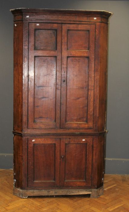 A George III oak floorstanding corner cupboard, the moulded cornice over a pair of panelled doors