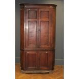 A George III oak floorstanding corner cupboard, the moulded cornice over a pair of panelled doors