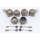 An Asian white metal six piece cruet set comprising pair of salts, pepper and mustard pots, embossed