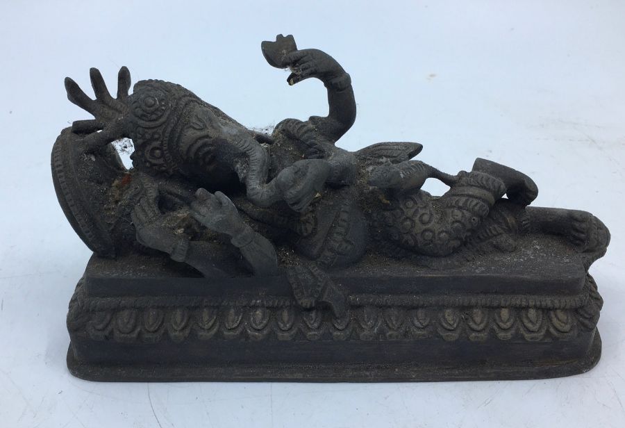 A 20th century Indian bronze figure of reclining four armed Ganesha, length 17.5cm.