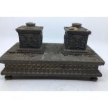 An early 20th century Indian bronze inkwell stand, the twin inkwell supports embossed panel of