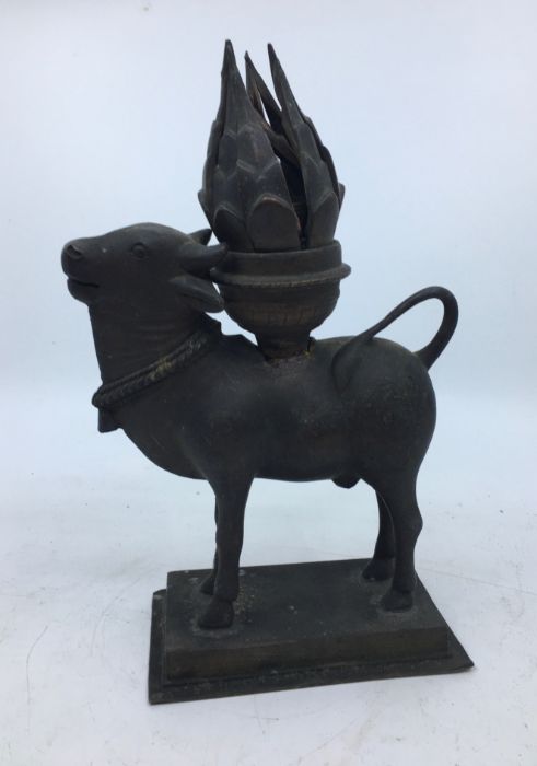 A 20th century Indian cupro-bronze lamp, fashioned as a cow carrying hinged flower form lamp, height