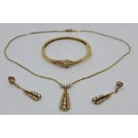 An 18ct. gold and diamond pendant necklace, hinged bangle and drop earrings en suite, the pendant