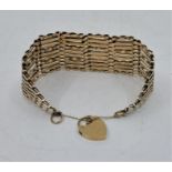 A wide 9ct. gold gate bracelet, with 9ct. gold heart padlock clasp, width 3.4cm, length approx. 18.