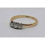 An 18ct. gold and platinum three stone clear stone ring, set row of three round cut clear stones (