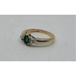 A 9ct. gold, emerald and diamond ring, claw set oval mixed cut emerald to centre with three round