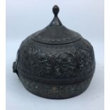 A 20th century Indian hinged hat box, fashioned as a helmet, the sides repousse various deities,
