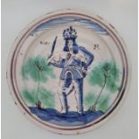 A late 17th century William III (1650-1702) English Delftware charger, painted in blue and green,