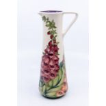 Moorcroft Pottery tall slender jug in 'Foxglove' pattern. Height approx 24cm. No signs of damage