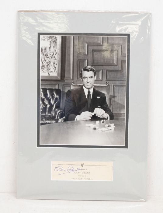 CARY GRANT - Signed / Autographed Display - A black and white photograph of Cary sitting at a desk