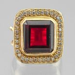 Importante bague En or jaune 585 millièmes, sertie d'une pierre rouge dans un entourage de diamants.