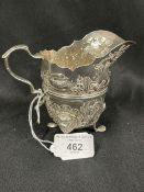 Hallmarked Silver (Irish): Helmet cream jug embossed with country scenes, with a C scroll handle,