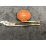 Jewellery: Yellow metal bar brooch 50mm long, at the centre is set an 18.5mm round piece of pink