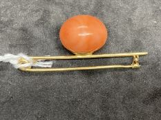 Jewellery: Yellow metal bar brooch 50mm long, at the centre is set an 18.5mm round piece of pink