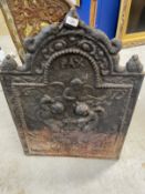 Cast iron fire back dated 1679, arched top, depicting angels working on the anvil. 31ins. x 23ins.