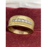 18ct gold band set with seven brilliant cut diamonds, estimated weight of (7) 0.15ct. Weight 5.9g.