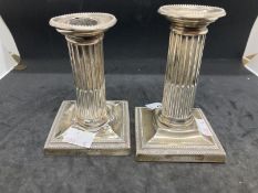 Hallmarked Silver: Dwarf Corinthian column candlesticks on square bases with faults, a pair.