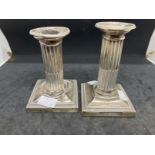 Hallmarked Silver: Dwarf Corinthian column candlesticks on square bases with faults, a pair.