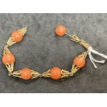 18ct gold and six 11.5mm evenly spaced coral beads as a bracelet. Weight 28.9g.