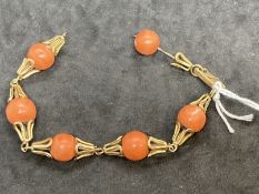 18ct gold and six 11.5mm evenly spaced coral beads as a bracelet. Weight 28.9g.