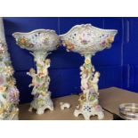 Early 20th cent. Dresden porcelain table centrepieces each with cherubs climbing amongst flowers,