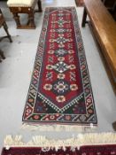 Carpets & Rugs: 20th cent. Kazak runner, red ground with stylised flowers and geometric design in