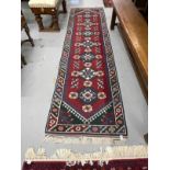 Carpets & Rugs: 20th cent. Kazak runner, red ground with stylised flowers and geometric design in