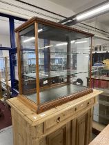 Early 20th cent. Display case, sliding glass doors to the back, two glass shelves on a moulded base.