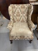 19th cent. Upholstered high wing back chair, front pad feet sloping rear supports. Height 43ins.