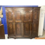 1920s mahogany break front wardrobe with castellated pelmet over four doors decorated with applied