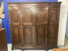 1920s mahogany break front wardrobe with castellated pelmet over four doors decorated with applied