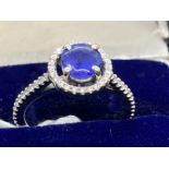 Jewellery: White metal ring in the form of a halo centre set with a circular cut tanzanite,