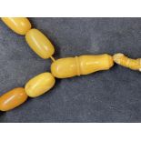 Jewellery: Necklet consisting of (33) butterscotch amber beads with a drop at the centre. Overall