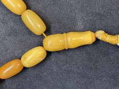 Jewellery: Necklet consisting of (33) butterscotch amber beads with a drop at the centre. Overall