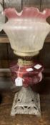 Victorian oil lamp cast iron base, cranberry glass reservoir vase line glass shade. 22ins.