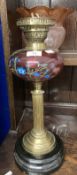 Victorian oil lamp black ceramic base, reeded brass column, cranberry glass reservoir with enamelled