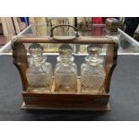 Late 19th cent. Oak Tantalus containing three cut glass decanters, silver plated mounts and