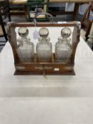 Late 19th cent. Oak Tantalus containing three cut glass decanters, silver plated mounts and