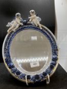 19th cent. Porcelain oval framed mirror, bevelled glass, decorated with cherubs and flowers. Approx.