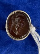 Jewellery: Yellow metal signet ring set with an oval garnet carved with centurion's head, tests as
