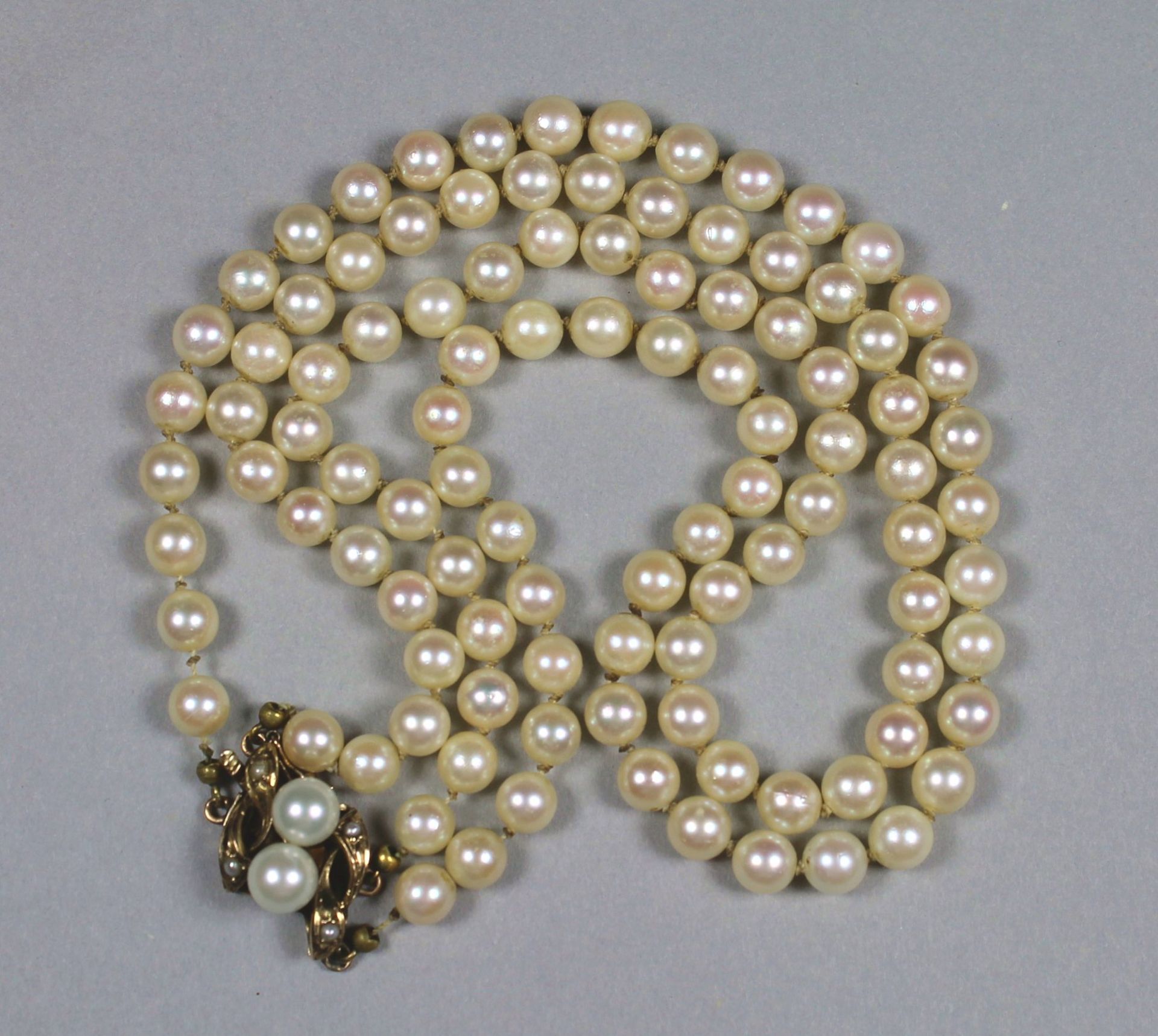 1 doppelreihiges Perlencollier, dekorativ gestalteter Verschluß 14kt.Gg (585/000), besetzt mit 2