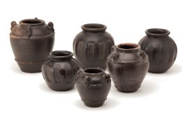 A GROUP OF SIX BLACK GLAZED TERRACOTTA JARS