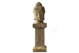 A STONE BUDDHA HEAD ON PLINTH