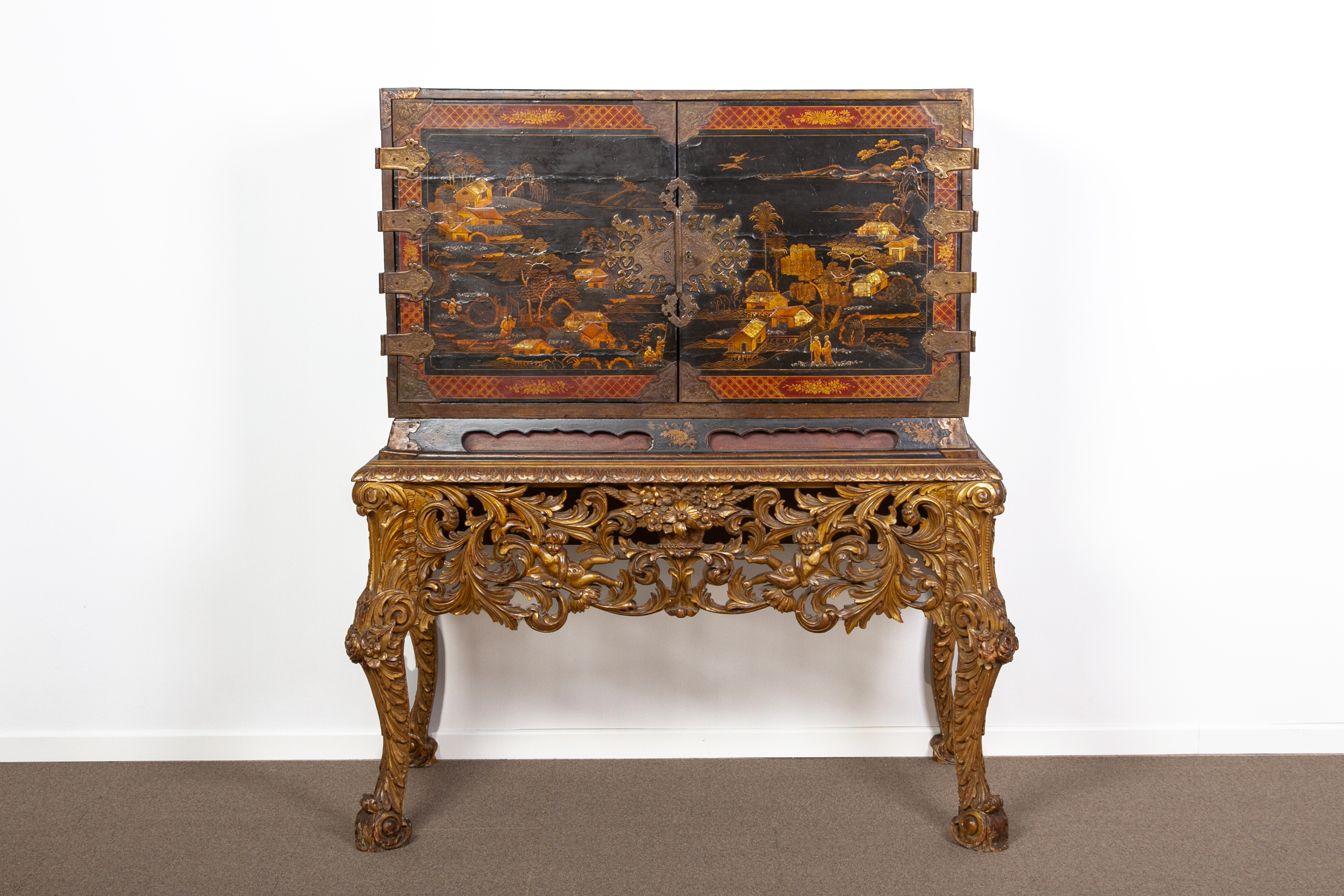 A BLACK LACQUER AND INLAID CABINET ON GILTWOOD STAND